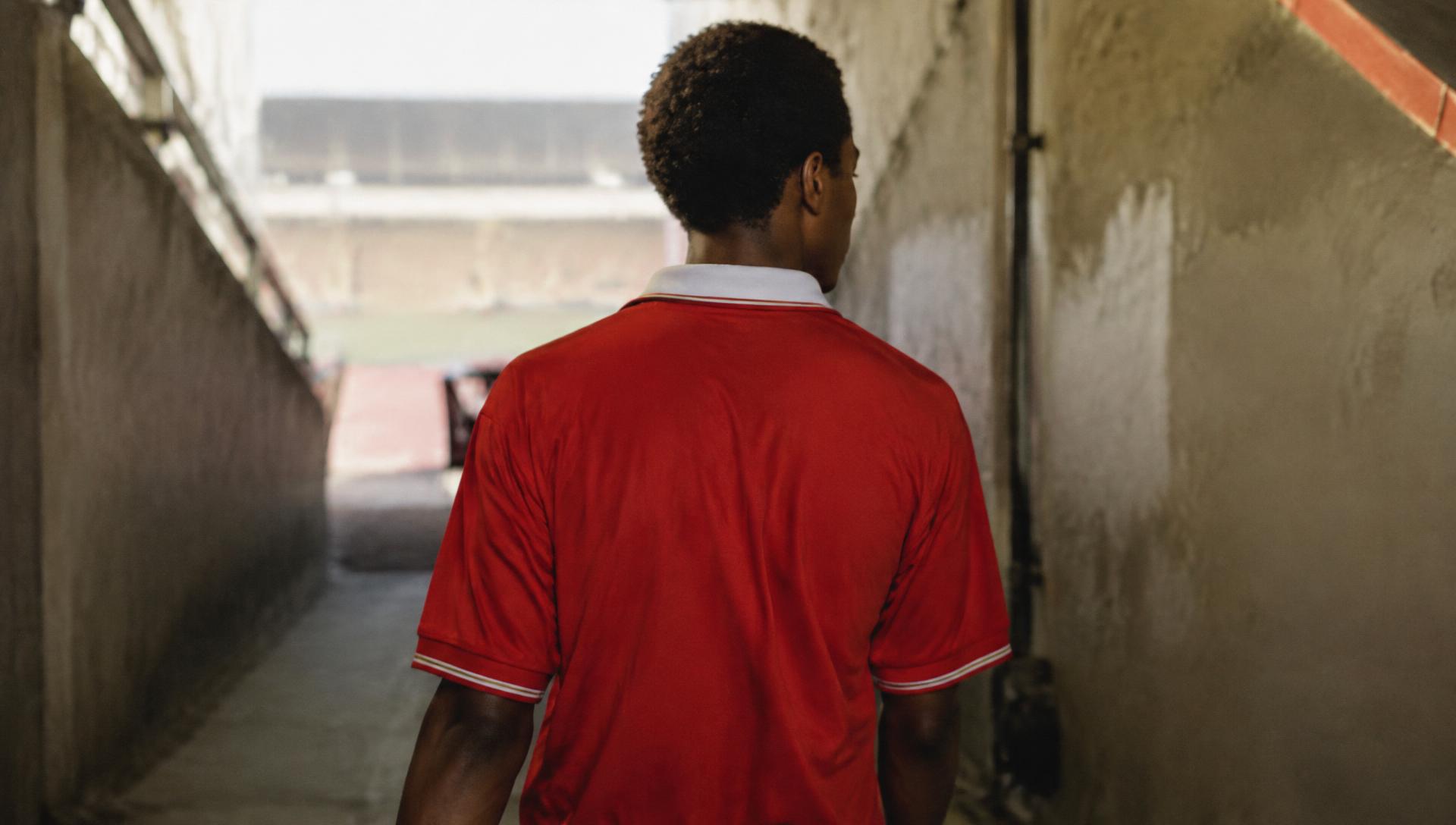Fan in a vintage red football shirt walking through a stadium tunnel